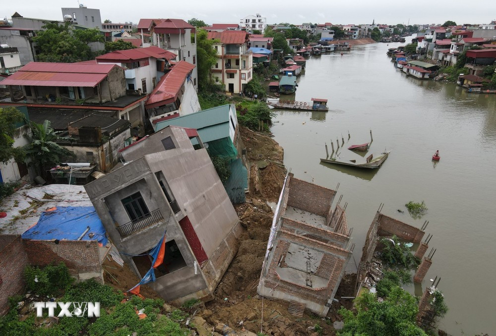 Hiện trường vụ sạt lở tại tuyến đê hữu sông Cầu đoạn qua khu Vạn Phúc, phường Vạn An (thành phố Bắc Ninh, tỉnh Bắc Ninh) khiến nhiều ngôi nhà bị rạn nứt, trôi xuống sông. (Ảnh: Thanh Thương/TTXVN)