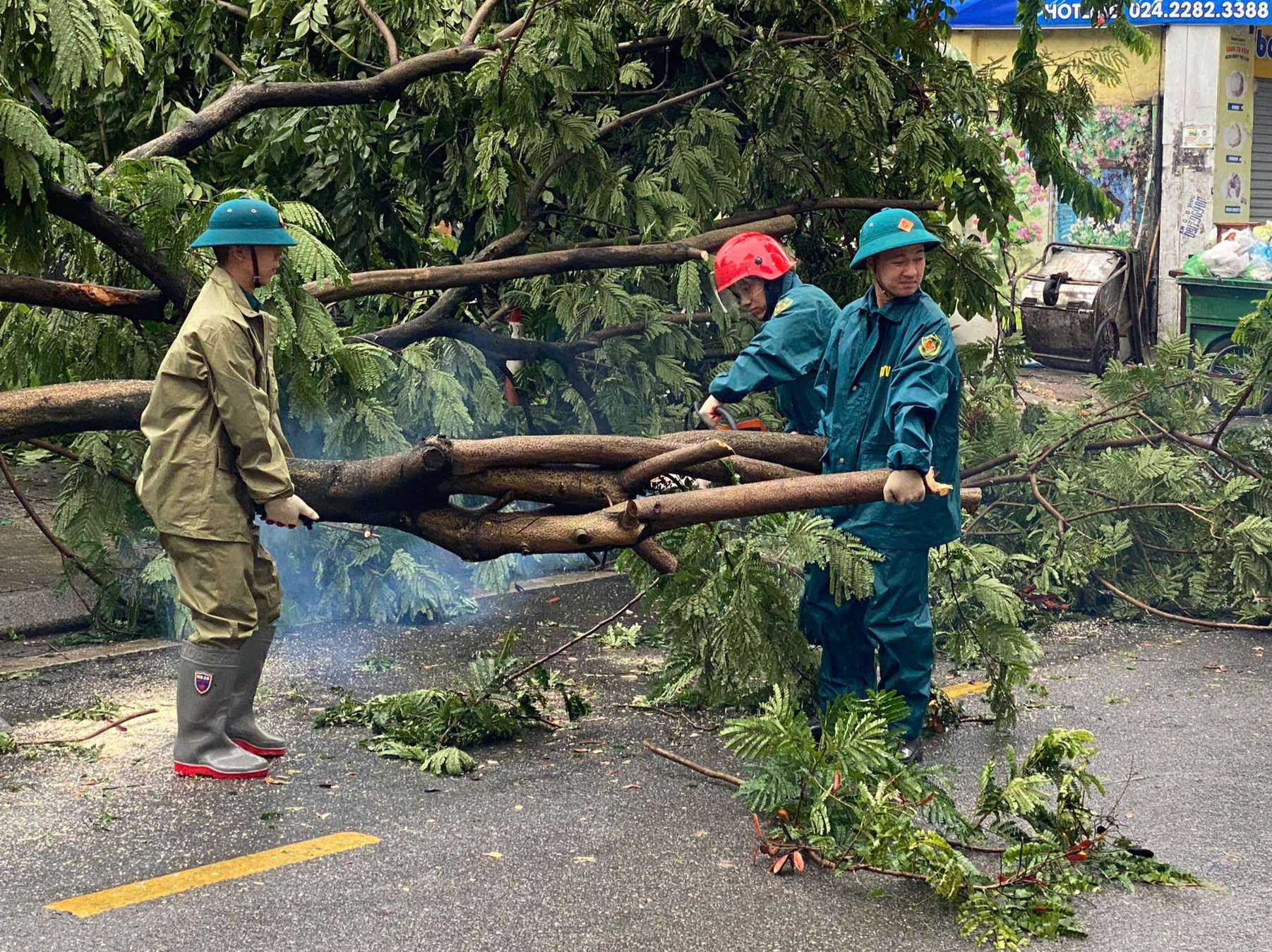 Lực lượng dân quân dùng phương tiện cắt cây trên phố Đội Cấn. Ảnh: Mai Hữu