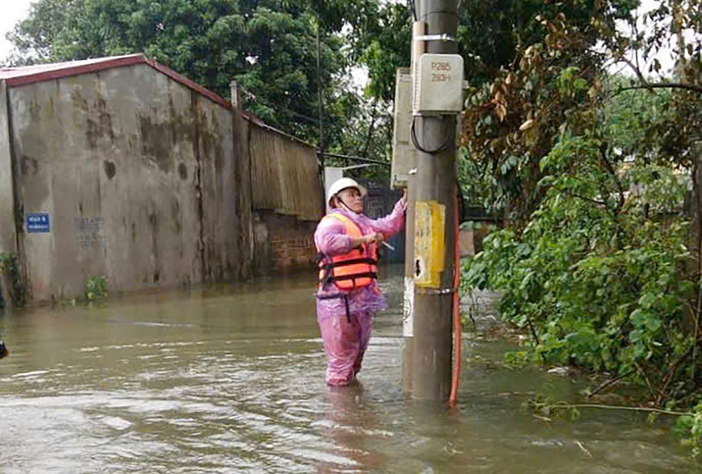 Nhân viên EVNHANOI không ngại khó khăn lao vào vùng bị ngập sâu để kiểm tra, sữa chữa.