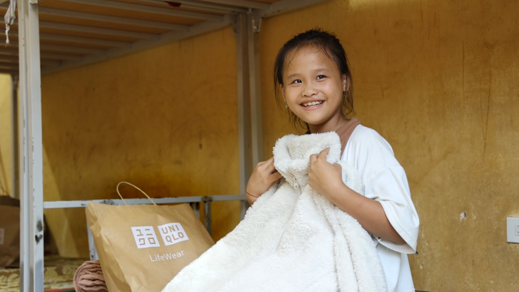 Một em học sinh hớn hở khi được nhận quần áo từ chương trình RE.UNIQLO