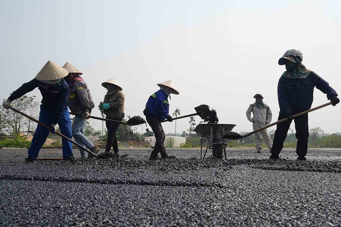 Máy móc, công nhân được huy động thảm nhựa mặt đường. Ảnh: Hữu Chánh