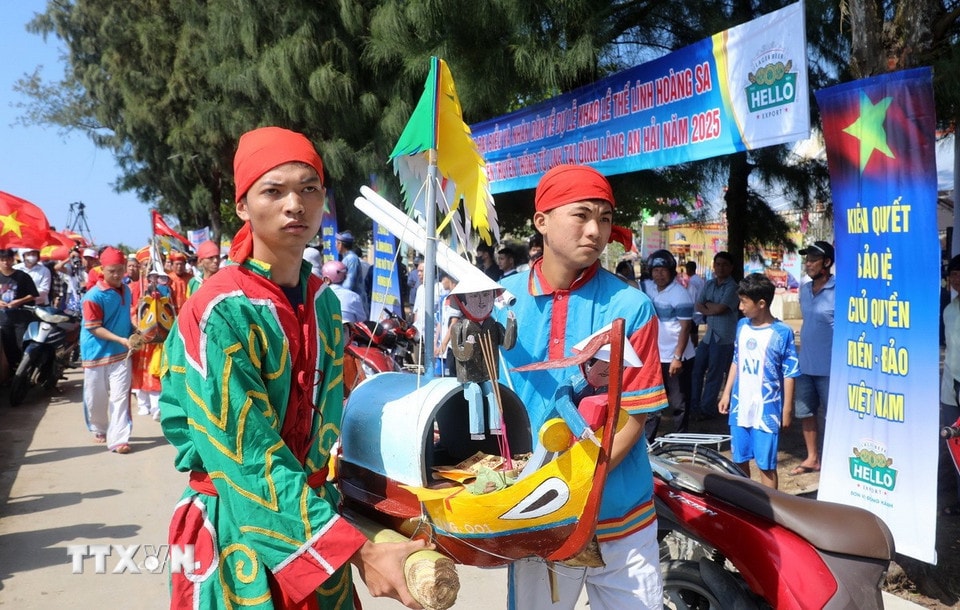 Các thanh niên ưu tú trong làng An Hải thực hiện nghi thức rước thuyền câu ra biển. (Ảnh: Quốc Khánh/TTXVN)