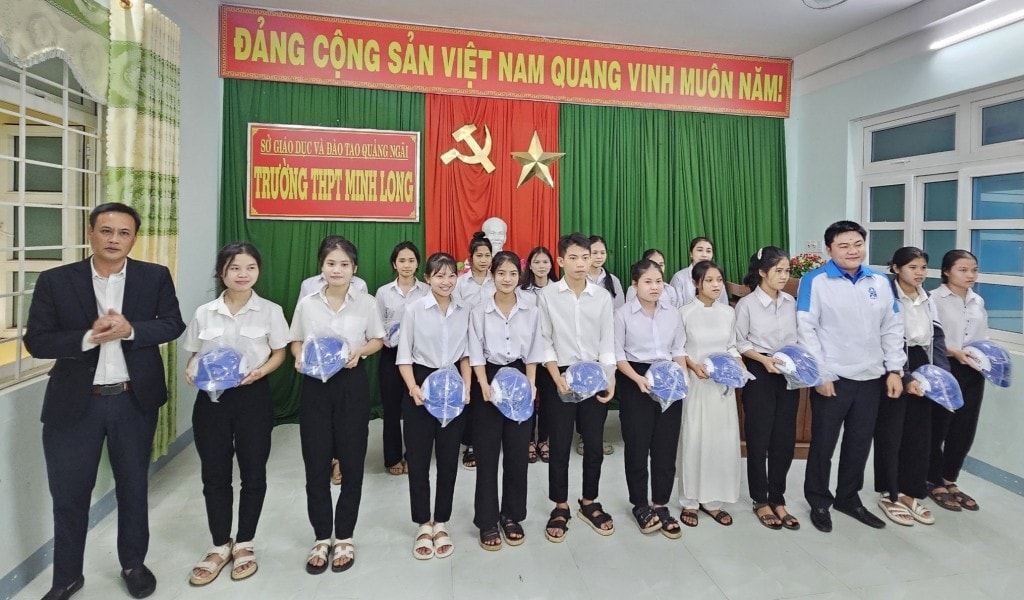 Đồng chí Trần Đăng Minh, Phó Bí thư Tỉnh đoàn Quảng Ngãi và nhà báo Bùi Ngọc Dương trao tặng mũ bảo hiểm cho các em học sinh 
