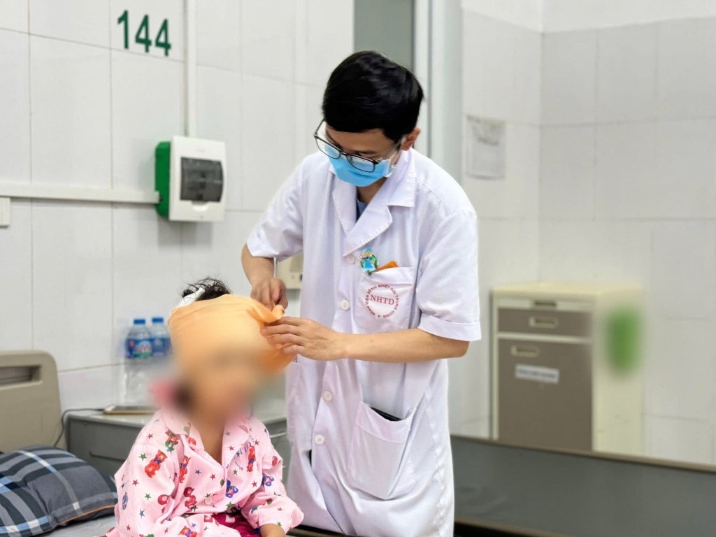 Bác sĩ thăm khám cho bé gái với 10 mũi khâu ở đầu và mặt