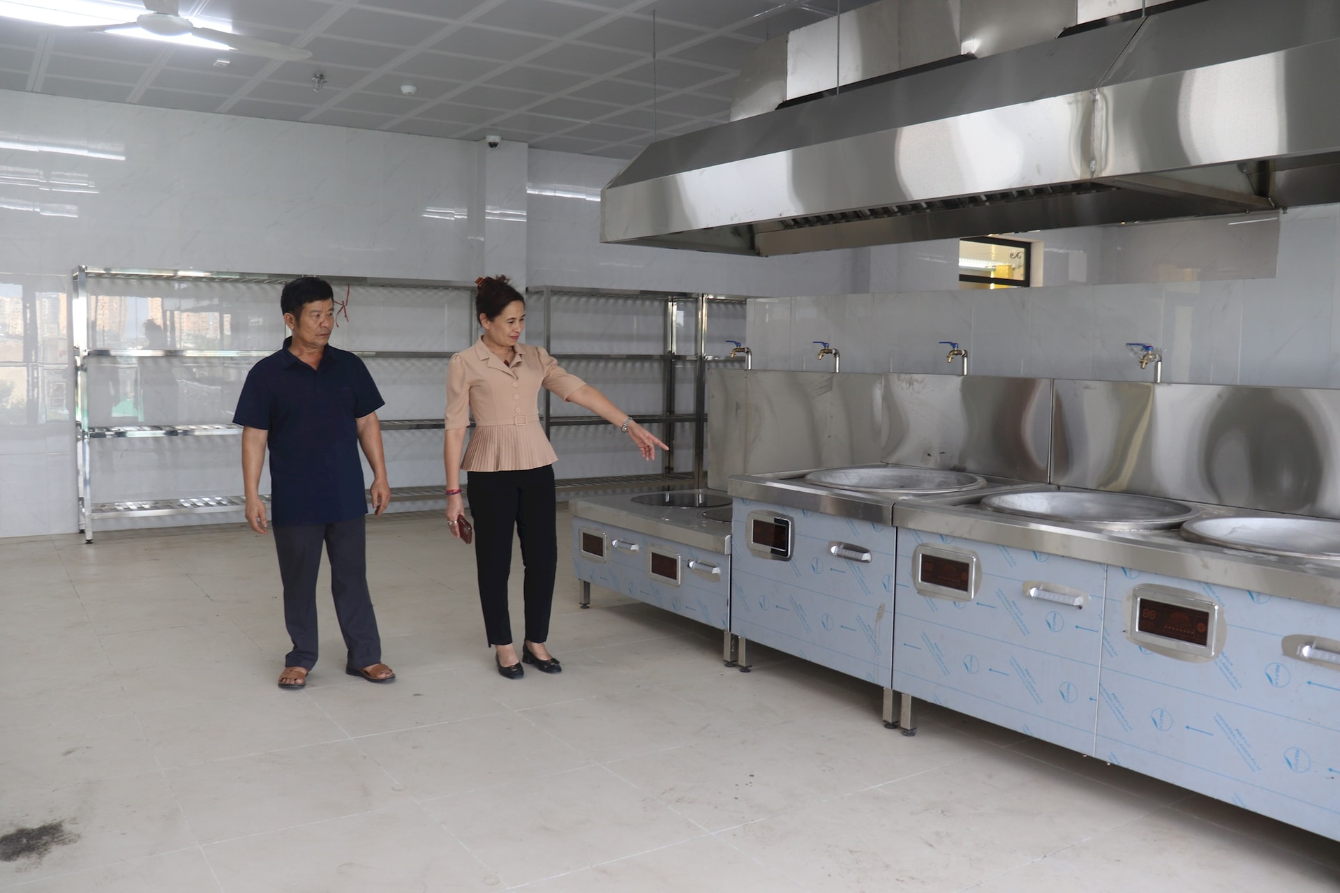 Bà Đinh Thị Ngọc Lan, Hiệu trưởng Trường Mầm non Định Công giới thiệu khu bếp hiện đại được đầu tư tại địa điểm Trường Mầm non Sao Mai mới xây trên địa bàn phường. Ảnh: Hiền Thu