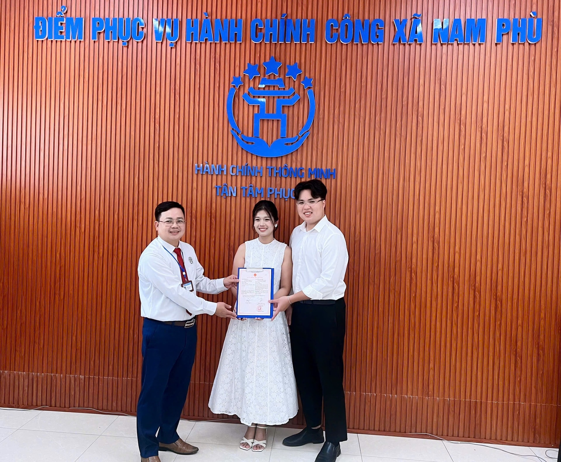 Phó chủ tịch UBND xã Nam Phù Nguyễn Văn Sung (ngoài cùng bên trái) trao giấy chứng nhận kết hôn cho vợ chồng anh Long, chị Vy. Ảnh: Phương Xuyến.