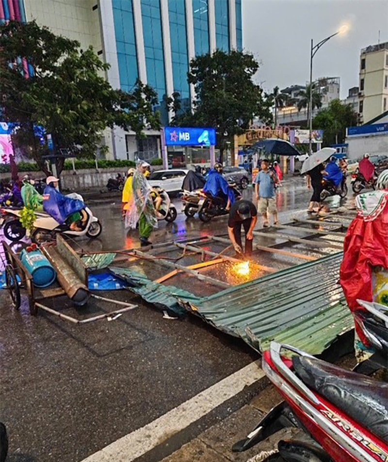 Một tấm biển quảng cáo bị kéo đổ văng ra đường, và lực lượng chức năng đã có mặt để xử lý
