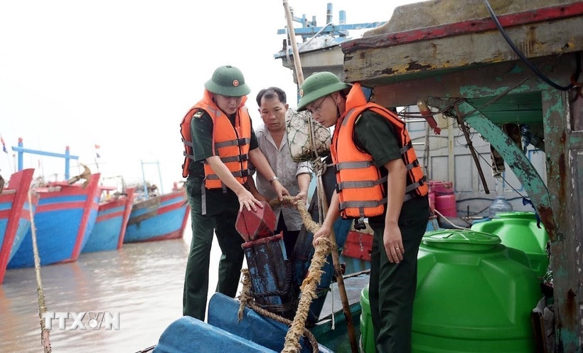 Lực lượng chức năng hướng dẫn, giúp ngư dân xã Hải Thịnh (Ninh Bình) phòng chống bão. (Ảnh: Thái Thuần/TTXVN)