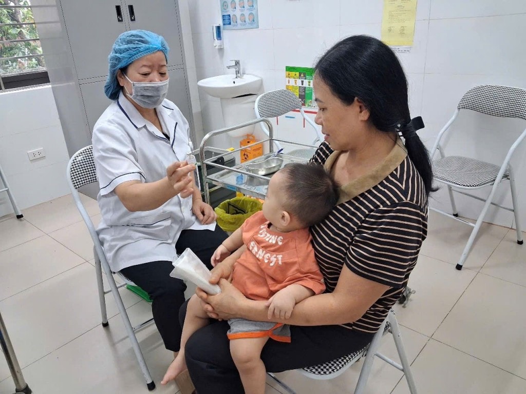 Người dân đưa trẻ đến tiêm chủng tại trạm y tế xã Quang Minh 