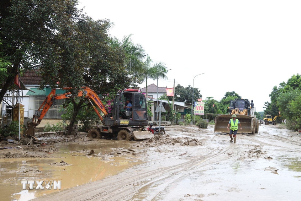 Máy cẩu, máy xúc được huy động tham gia vào việc san ủi bùn đất, sình lầy tại một điểm ngập trên tuyến quốc lộ 7 qua địa bàn xã Con Cuông, tỉnh Nghệ An. (Ảnh: Xuân Tiến/TTXVN)
