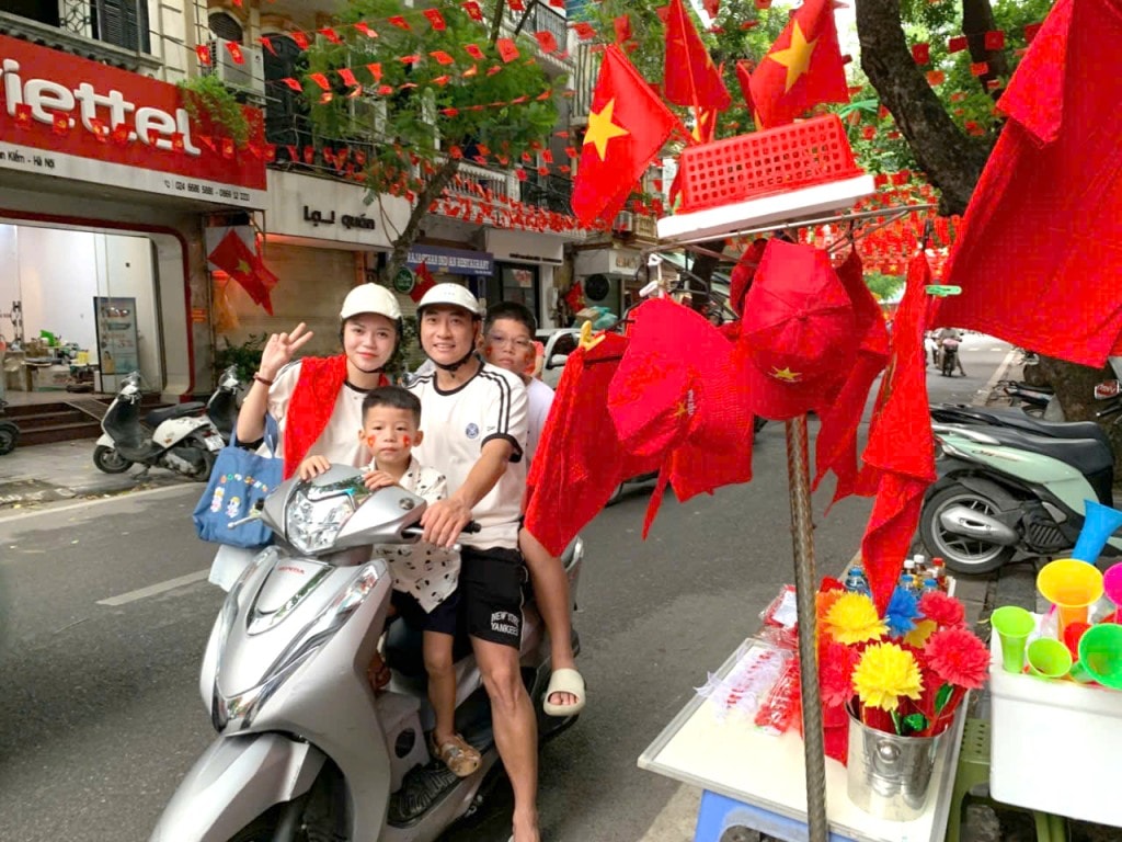 Vợ chồng bạn Nguyễn Văn Tùng ở phố Hoàng Hoa Thám (Hà Nội) cho các con đi phố mua cờ về đón mừng Tết Độc lập