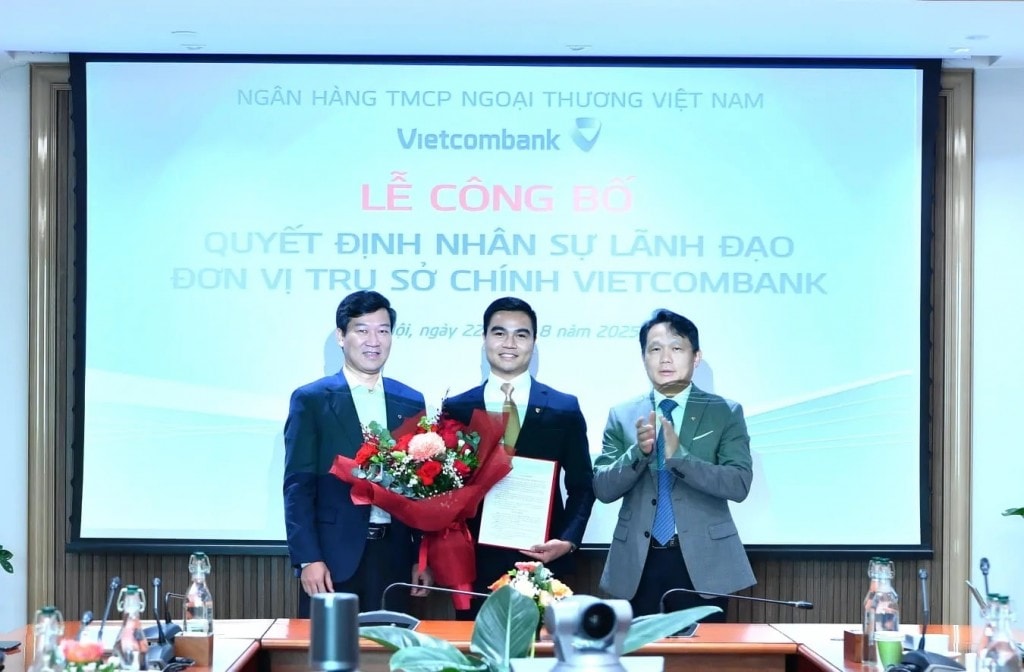 Ông Vũ Quang Đông - Phó Giám đốc Khối phụ trách Khối Vốn và Thị trường Vietcombank (bên trái) trao Quyết định bổ nhiệm và ông Nguyễn Mạnh Hùng - Thành viên HĐQT Vietcombank (bên phải) tặng hoa chúc mừng ông Nguyễn Hữu Tùng - tân Phó giám đốc Ban Kinh doan