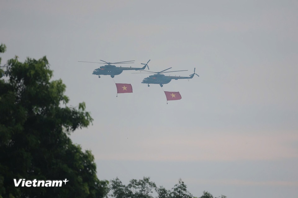Hình ảnh những chiếc trực thăng kéo theo lá cờ đỏ sao vàng khổng lồ tung bay kiêu hãnh giữa nền trời thu khiến người dân trầm trồ, nhiều ánh mắt dõi theo đầy xúc động. (Ảnh: PV/Vietnam+)