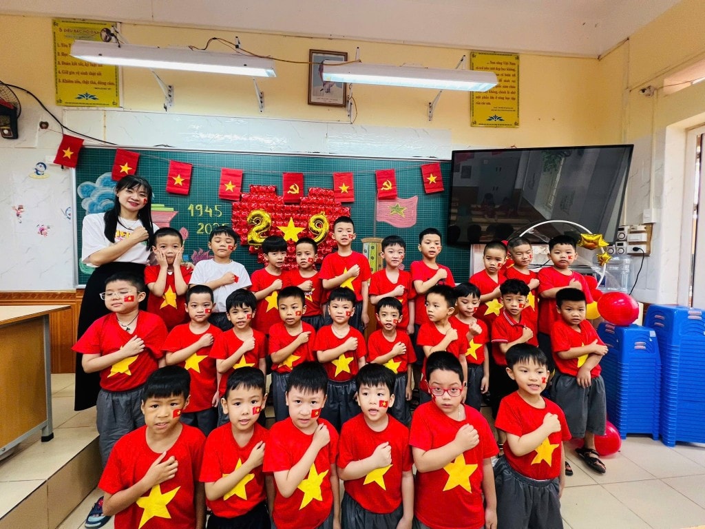 Các em học sinh trong lớp khoác áo đỏ sao vàng, tạo hình trái tim, thể hiện tình yêu quê hương đất nước.