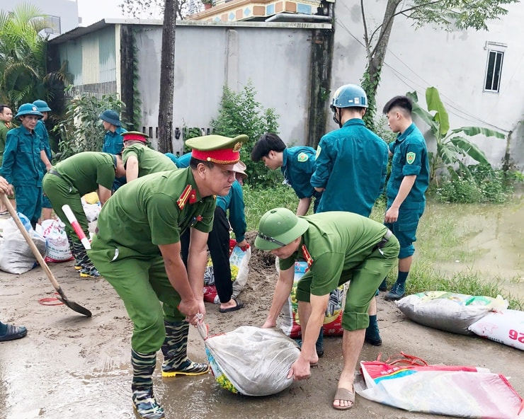 Politi og milits i Quang Bi kommune prøver å heve diket for å hindre flom i å komme inn i boligområder og jorder. Foto: Minh Than