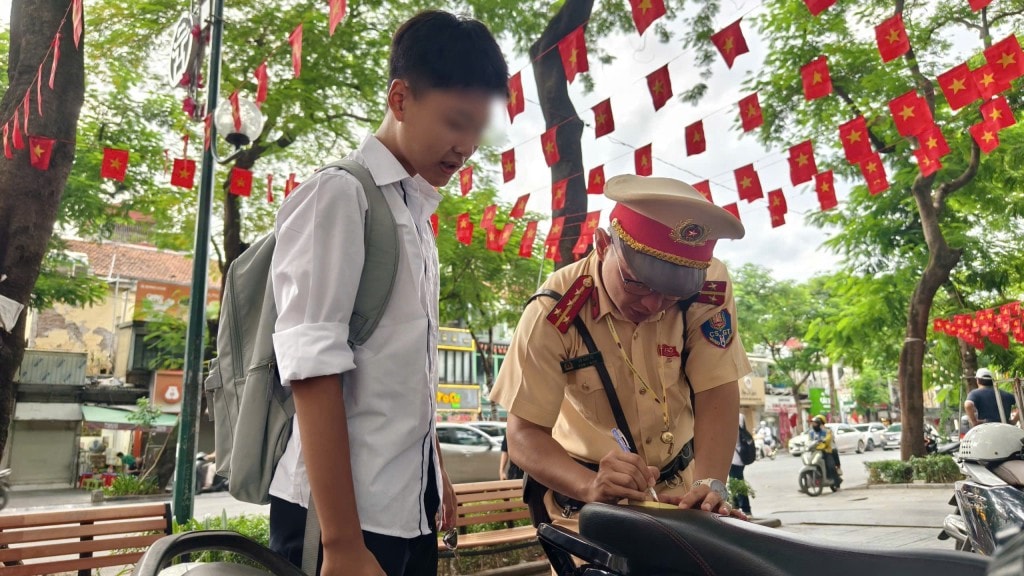 Một học sinh ký cam kết, ghi rõ nội dung vi phạm giao thông dưới sự hướng dẫn của lực lượng chức năng.