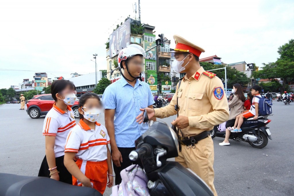 Cảnh sát giao thông trao đổi với phụ huynh và học sinh vi phạm ngay tại nút giao thông đông đúc ở trung tâm thành phố.