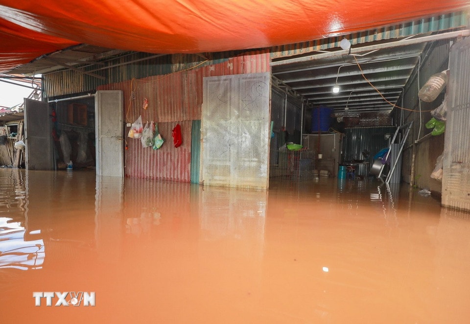 Nhiều nhà dân sát chân cầu Long Biên chiều nay đã ngập sâu trong nước. (Ảnh: Phan Phương/TTXVN)