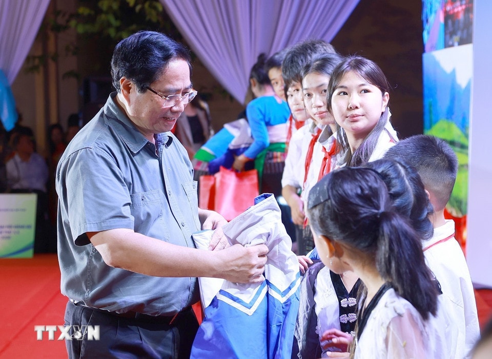 Thủ tướng Phạm Minh Chính tặng áo ấm cho học sinh xã Bát Mọt. (Ảnh: Dương Giang/TTXVN)