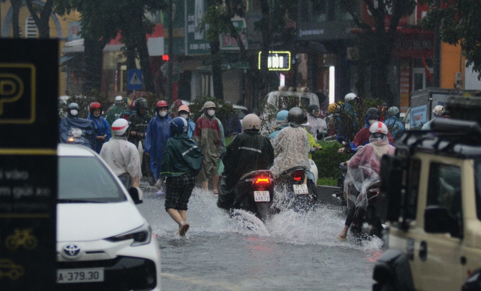 Người dân cố gắng đi qua đoạn đường ngập. (Ảnh: Văn Dũng/TTXVN)