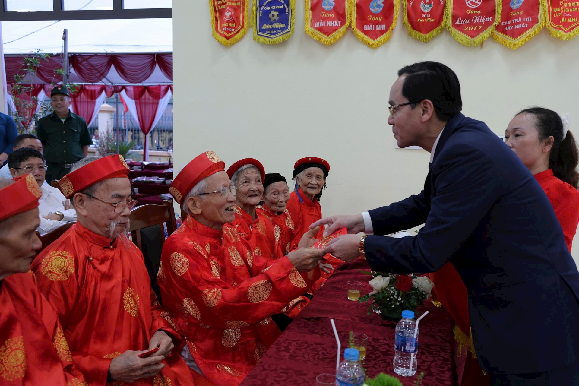 Bí thư Đảng ủy, Chủ tịch HĐND xã Phú Nghĩa Trịnh Tiến Tường mừng thọ các cụ cao niên tại Ngày hội Đại Đoàn kết. Ảnh: Kim Thoa