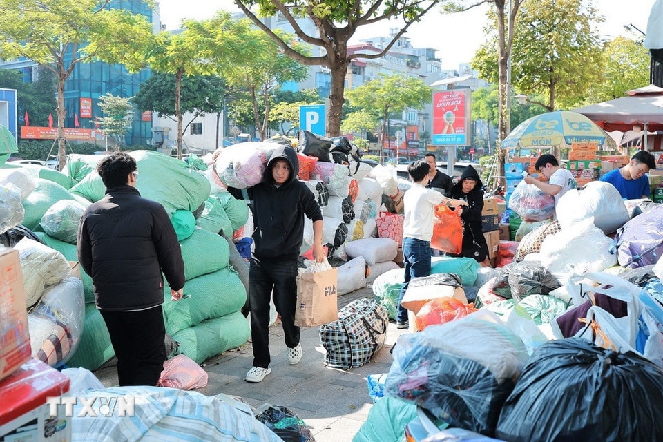Tình nguyện viên phân loại và đóng gói quần áo để gửi tới đồng bào miền Trung tại điểm Ô Chợ Dừa. (Ảnh: Lê Đông/TTXVN)