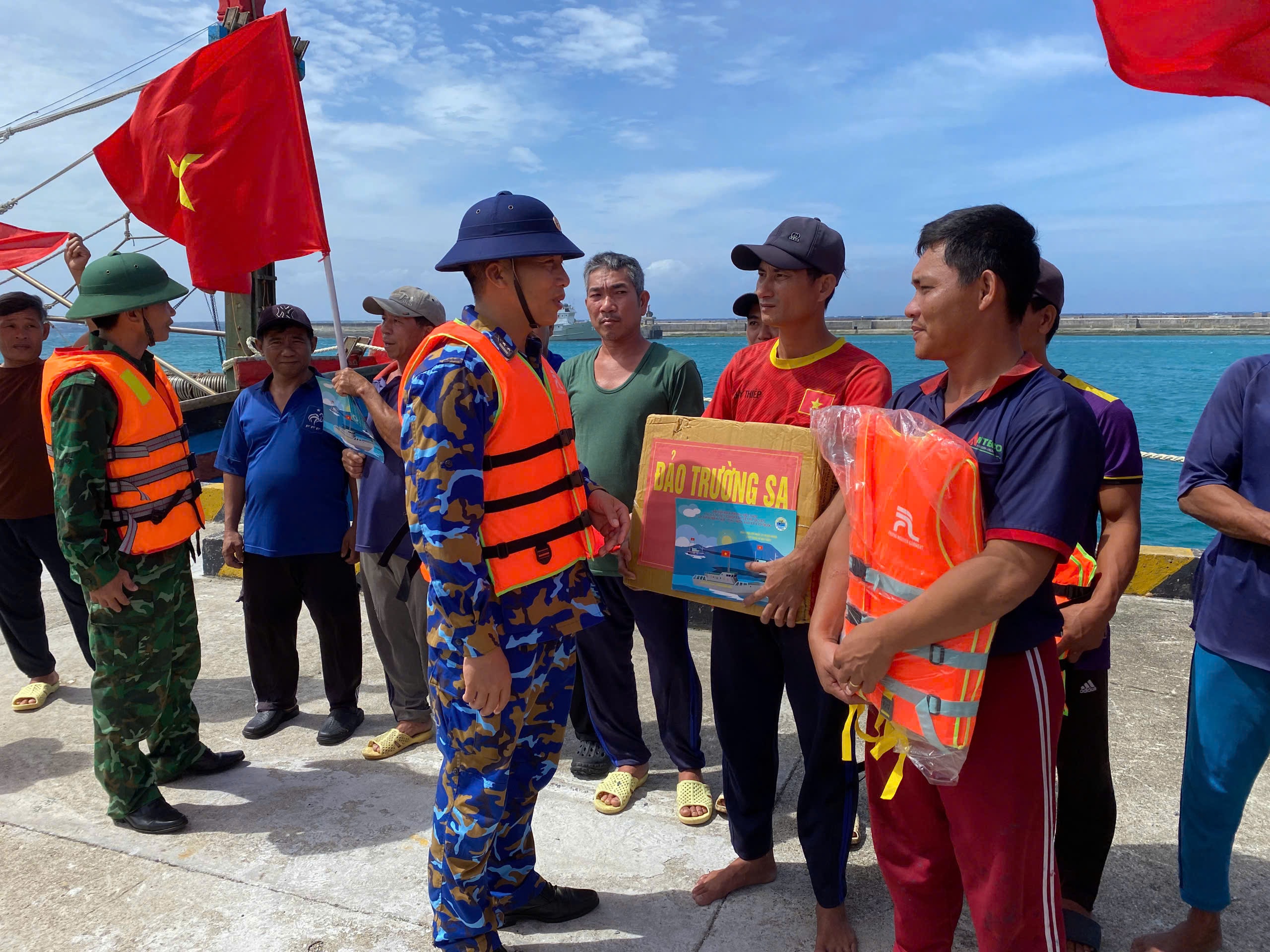 Cán bộ, chiến sĩ đảo Trường Sa lớn tặng quà và động viên ngư dân vào âu thuyền tránh sóng lớn. Ảnh: Ngọc Ánh.