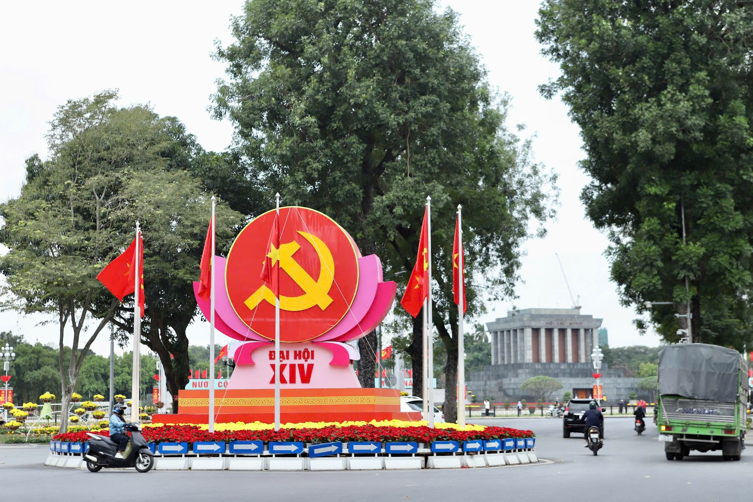 Biểu trưng Đại hội XIV với hình ảnh cờ đỏ, búa liềm vàng được đặt ở vị trí trung tâm, kết hợp cờ Đảng, cờ Tổ quốc và hoa trang trí, tạo nên những điểm nhấn trực quan giàu ý nghĩa chính trị.