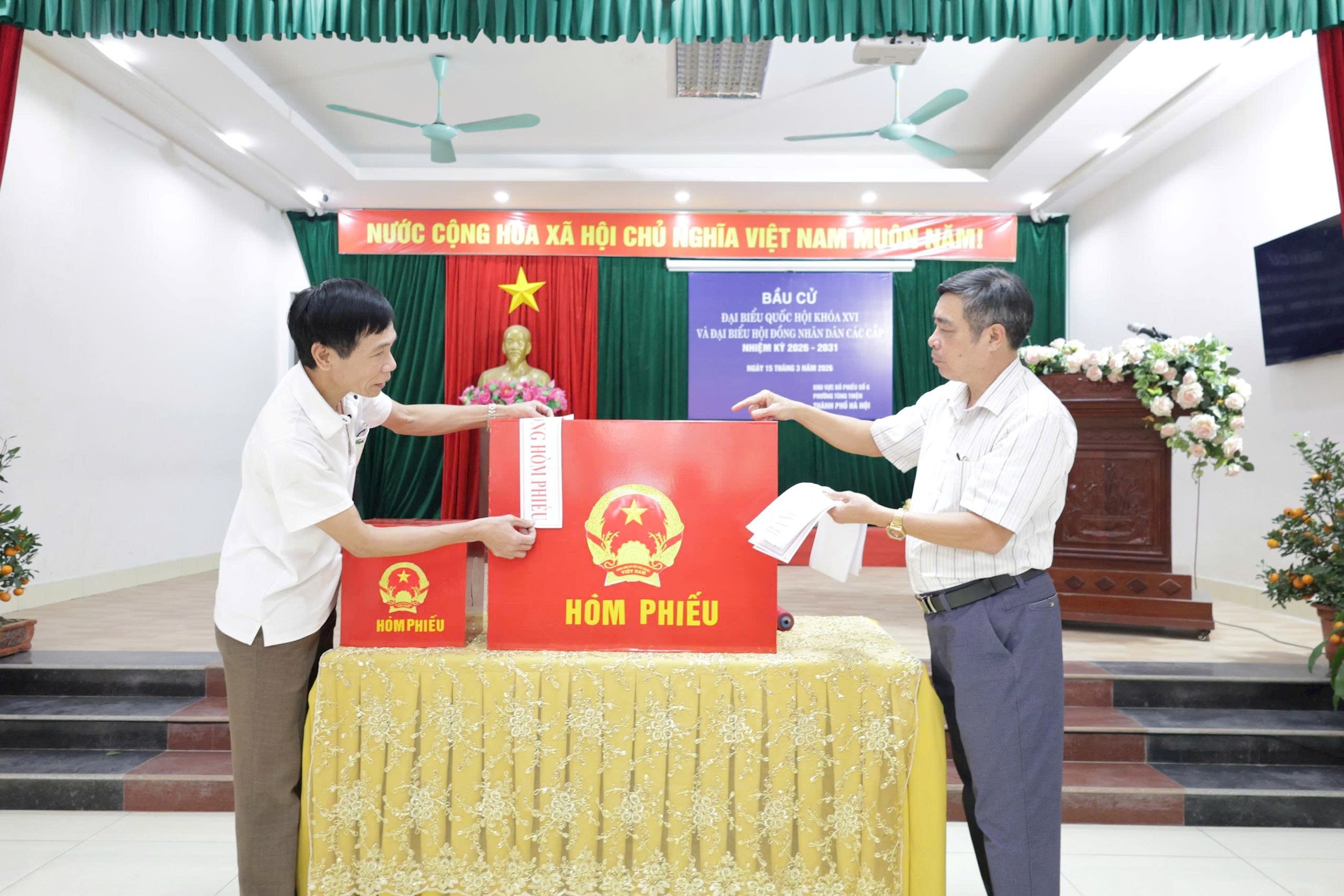Ông Phùng Hữu Nghị - Tổ trưởng Tổ bầu cử số 6 Tổ dân phố Sơn Lộc (bên phải) thực hiện niêm yết hòm phiếu. Ảnh: PL