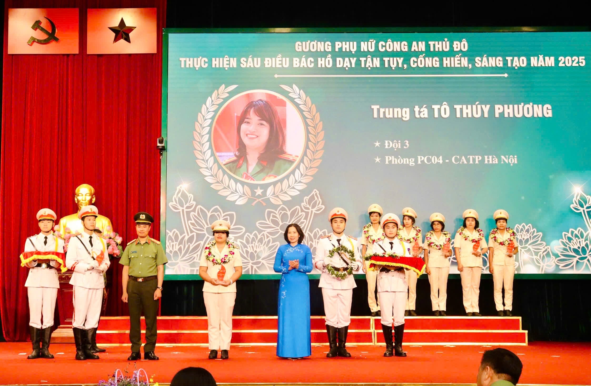 Chủ tịch Hội Liên hiệp phụ nữ thành phố Hà Nội Lê Kim Anh và Phó Giám đốc Công an thành phố Hà Nội Nguyễn Ngọc Quyền trao hoa và biểu trưng tôn vinh “Gương phụ nữ tiêu biểu, tận tụy năm 2025” cho Trung tá Tô Thuý Phương. Ảnh: Hồng Nhung