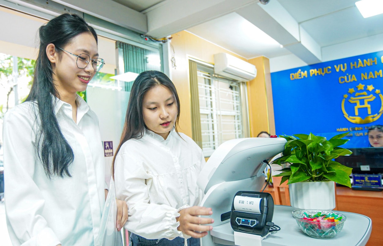 Le persone ottengono il numero tramite un robot AI presso un punto di servizio amministrativo di Nam Giang. - nam-giang-photo.jpg