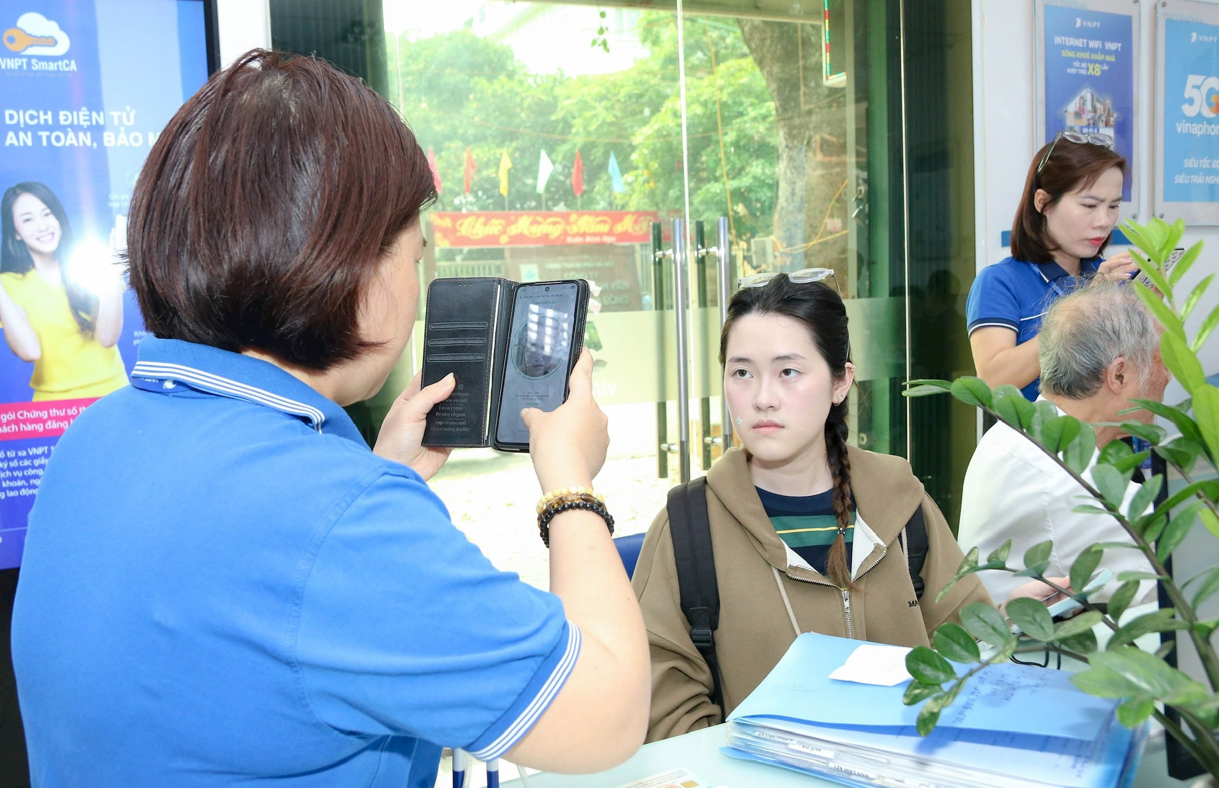 Personale di Vinaphone che scatta foto ai clienti che si registrano per gli abbonamenti nel quartiere di Ha Dong. - anh-huong-lan.jpg