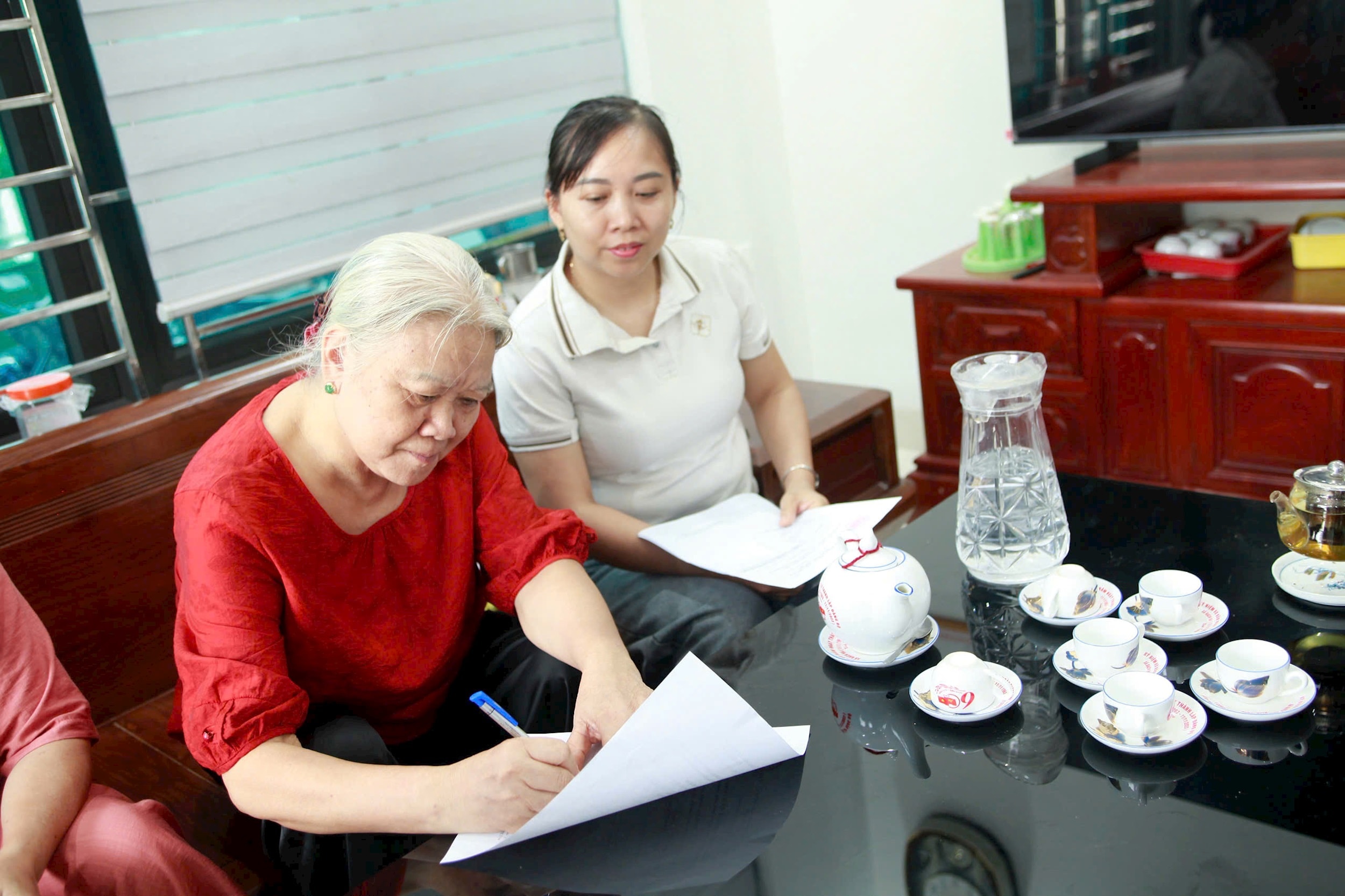 Bà Nguyễn Thị Lan ký nhất trí với phương án sắp xếp 4 thôn lại và đặt tên là thôn Bình Minh. Ảnh: Hồng Nhung
