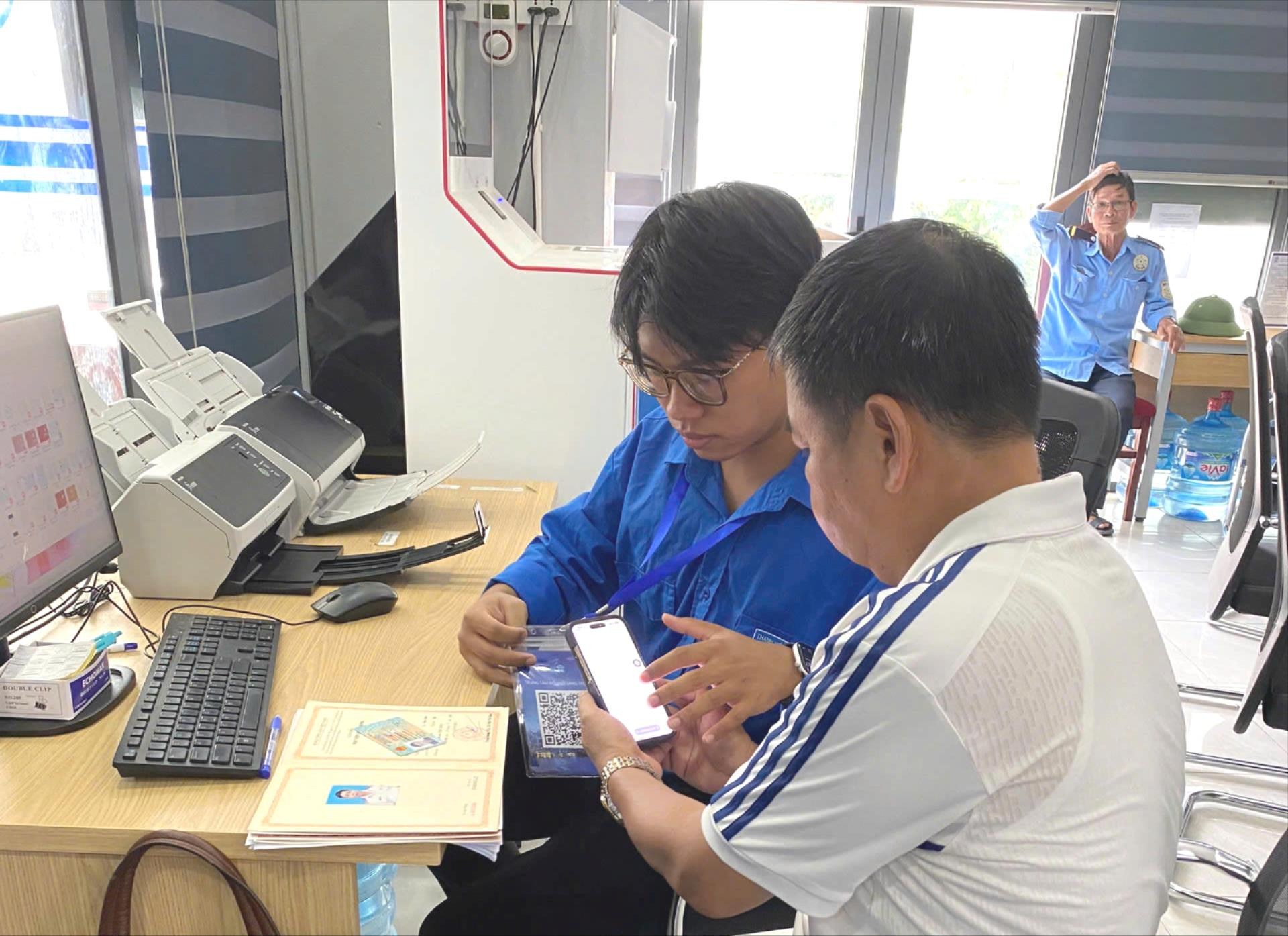 Đoàn viên Nguyễn Thanh Tú hỗ trợ người dân quét mã QR và thực hiện khảo sát điện tử. Ảnh: PT