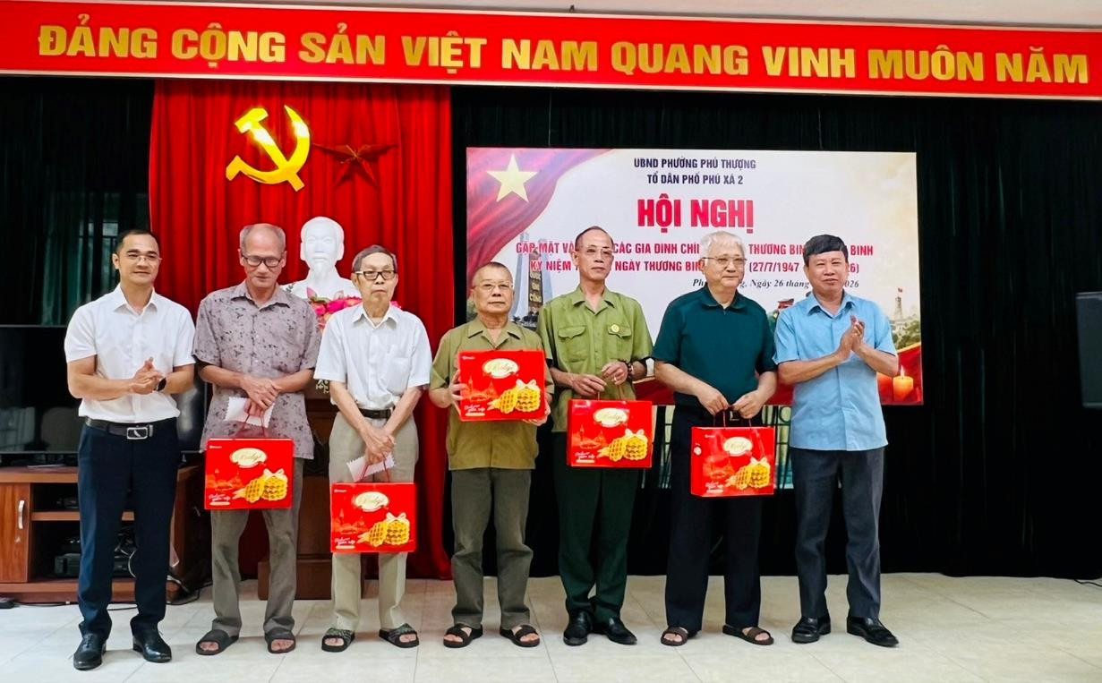 Trưởng ban Xây dựng Đảng phường Phú Thượng Nguyễn Mạnh Hải (bên phải) và Bí thư Chi bộ tổ dân phố Phú Xá 2 Vũ Văn Phong (bên trái) trao quà tri ân các thương binh, bệnh binh, gia đình người có công. Ảnh: Tuệ Lâm