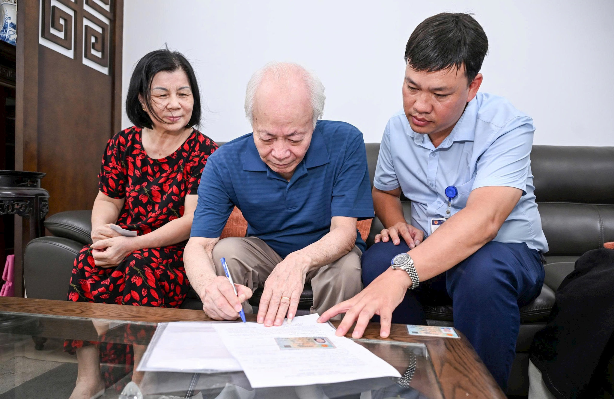Anh Lê Minh Thiện, cán bộ Điểm hỗ trợ dịch vụ công số Phương Liệt hỗ tlàm thủ tục ủy quyền nhận lương hưu tại nhà cho ông Nguyễn Xuân Bình. Ảnh: N.Đạt