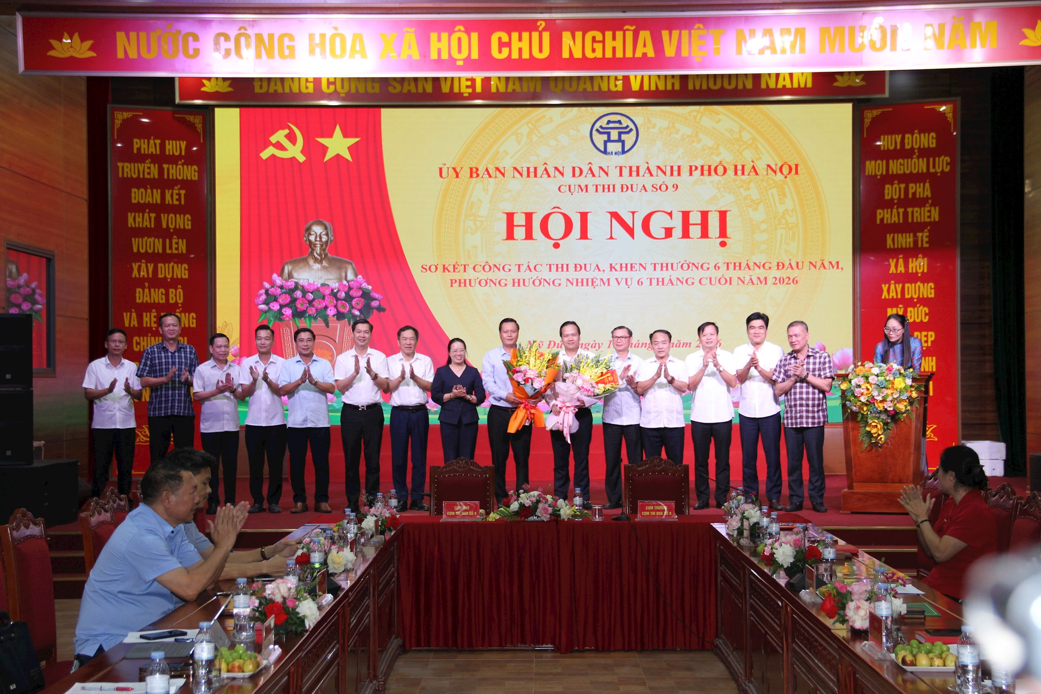 Các đồng chí lãnh đạo các đơn vị trong Cụm thi đua số 9 tặng hoa chúc mừng đồng chí Trần Đức Hải (thứ 9 từ trái qua), nguyên Bí thư Đảng ủy, Chủ tịch HĐND xã Hương Sơn được bổ nhiệm giữ chức vụ Giám đốc Sở Công Thương Hà Nội và đồng chí Ngô Văn Nam (thứ 6 từ phải qua), nguyên Bí thư Đảng ủy, Chủ tịch HD phường Đông Ngạc được bổ nhiệm giữ chức Bí thư Đảng ủy xã Hương Sơn. Ảnh: Biên Phạm
