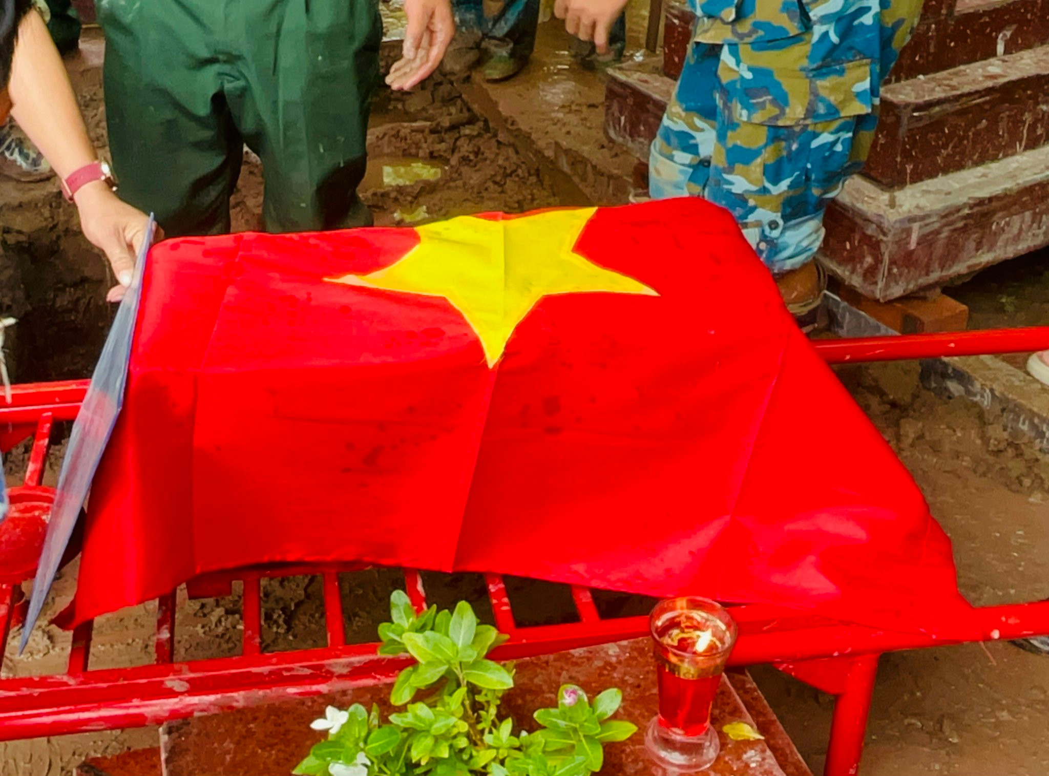 Quốc kỳ phủ trên phần hài cốt, biểu tượng của lòng tri ân với người đã hy sinh. Ảnh: Ánh Binh