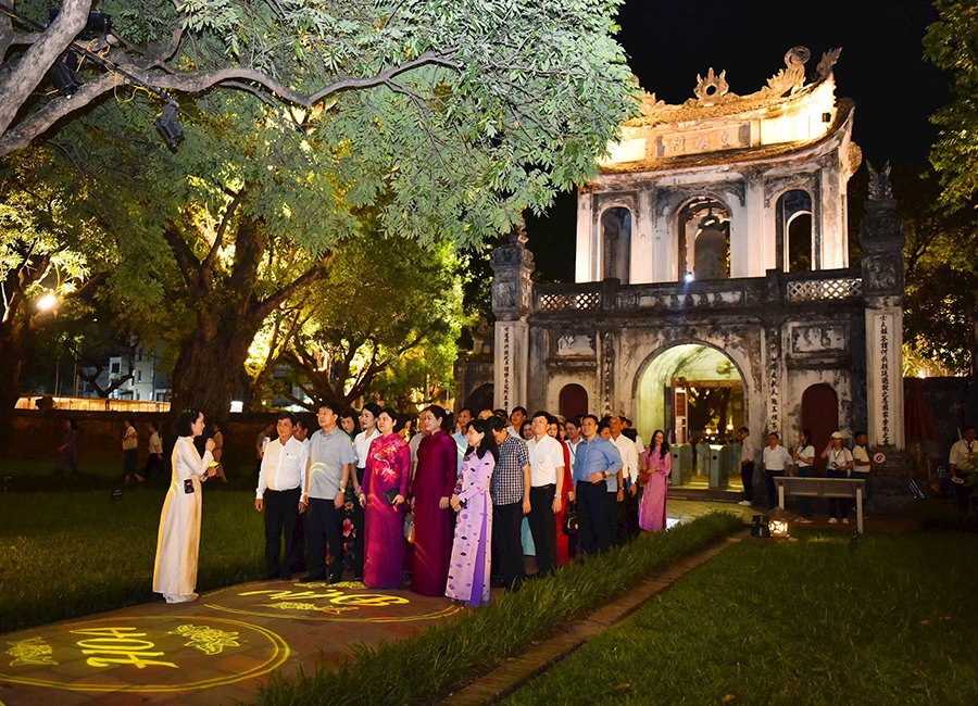 Du khách nghe giới thiệu về chương trình tour đêm “Tinh hoa đạo học” tại Di tích quốc gia đặc biệt Văn Miếu - Quốc Tử Giám. Ảnh: Nhật Nam