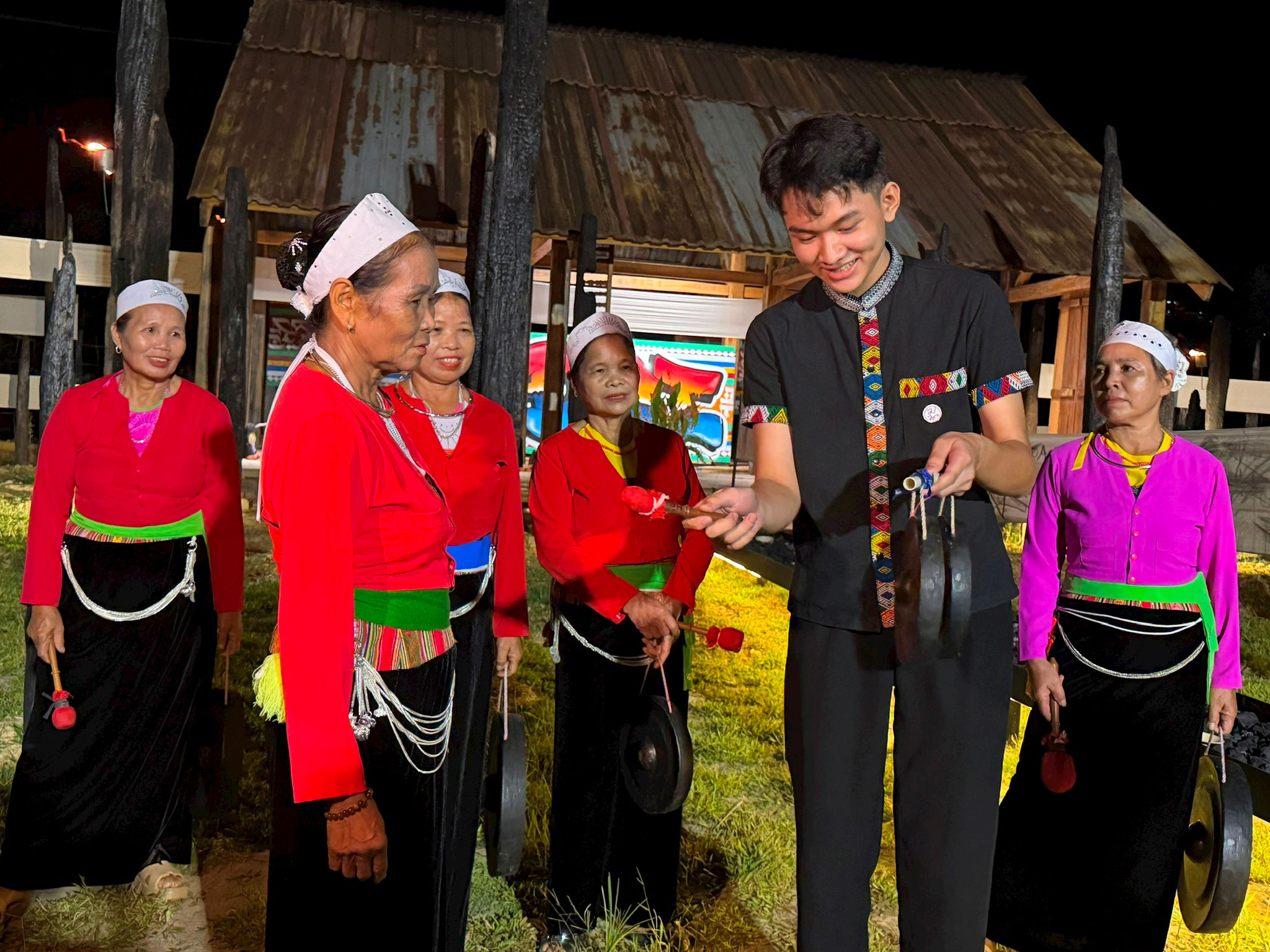 Người dân và du khách tìm hiểu và trải nghiệm thực hành đánh cồng chiêng Mường. Ảnh: Thụy Du