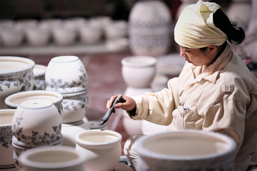 Người thợ làng gốm Bát Tràng tỉ mỉ trang trí hoa văn trên sản phẩm, gìn giữ nét tinh hoa của nghề truyền thống. Ảnh: PV