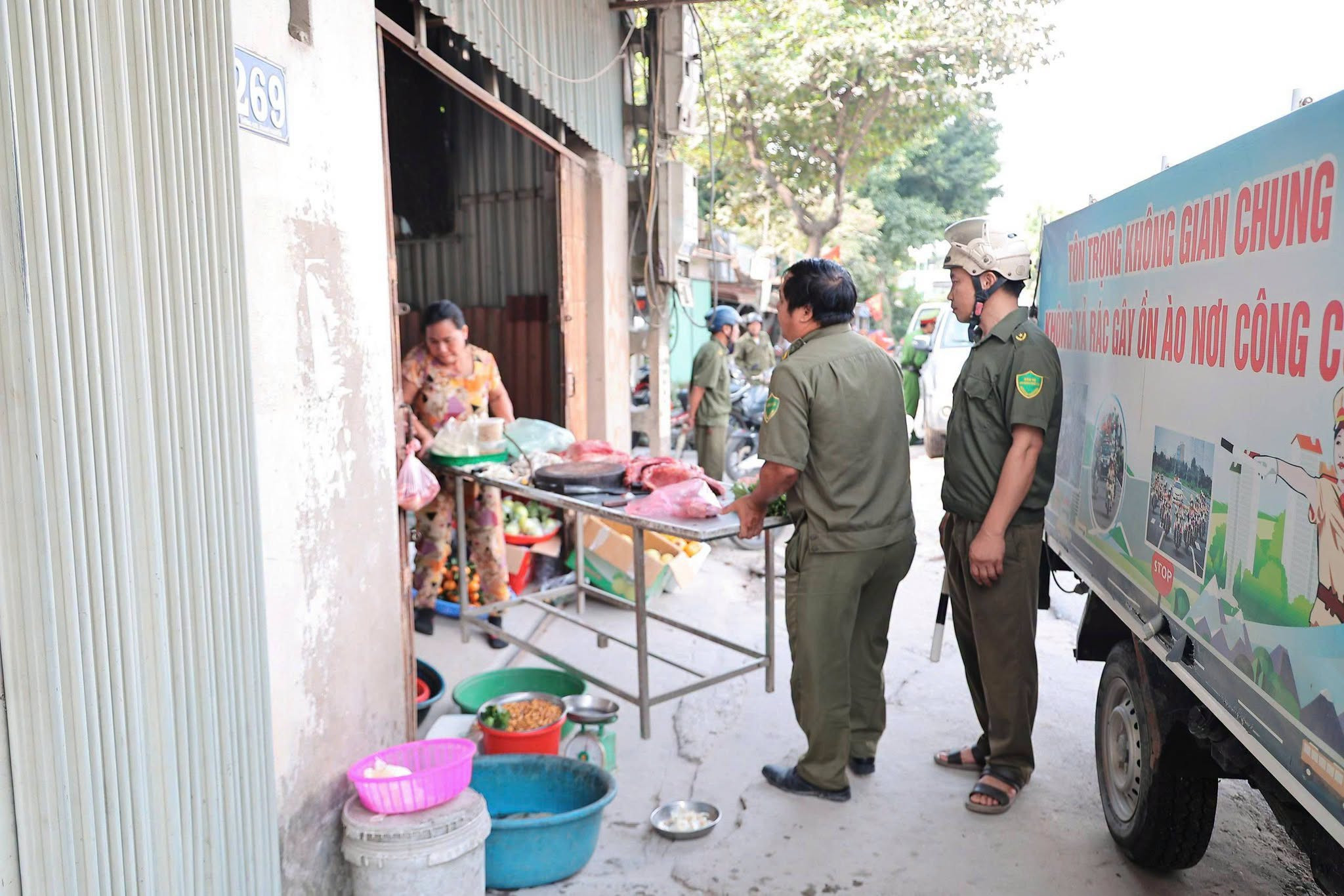 Các lực lượng hỗ trợ người dân thu dọn hàng hoá khỏi khu vực vỉa hè, lòng đường. Ảnh: Lê Hoa